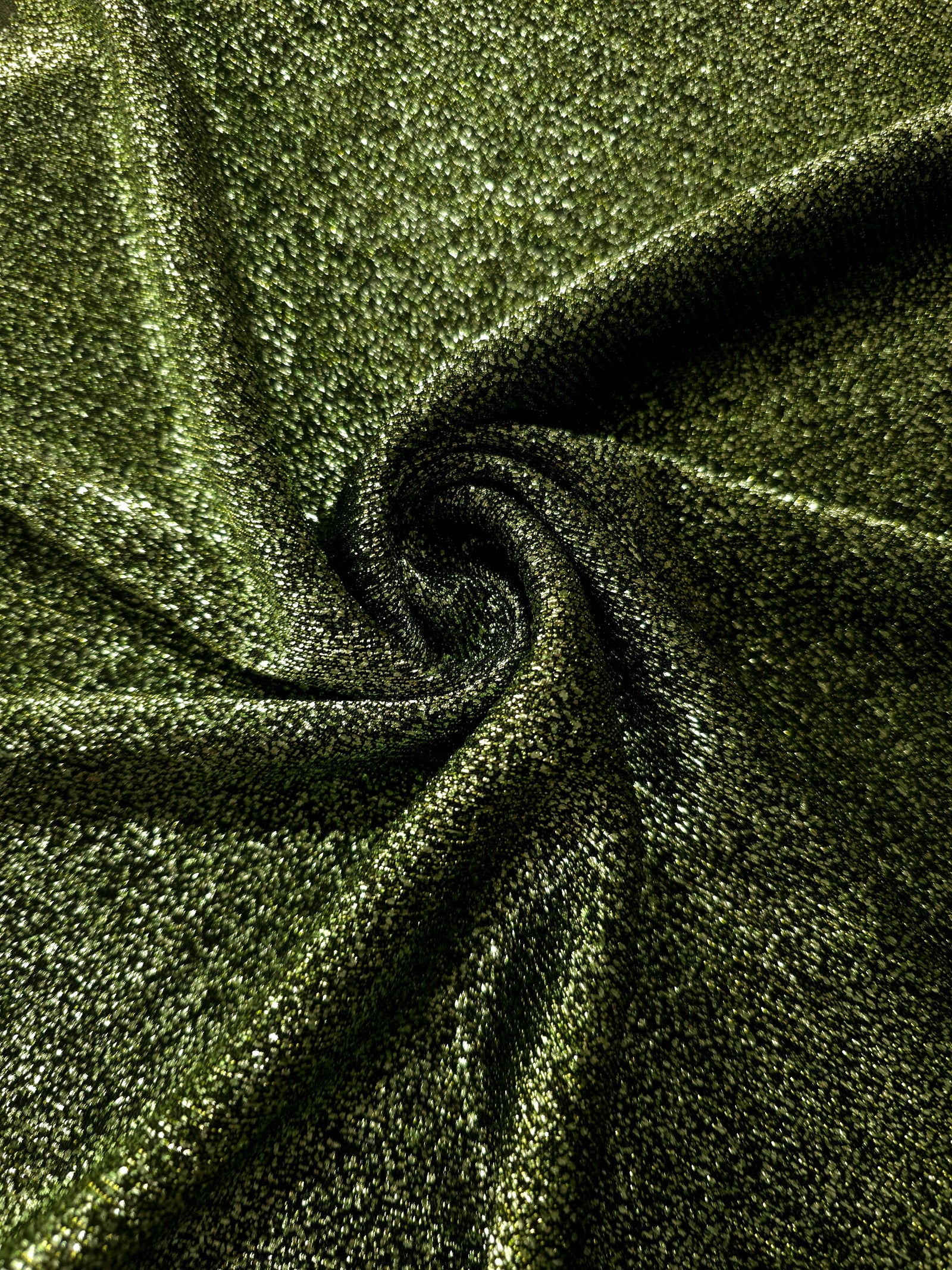 Swirl-draped Olive Green Sheer Glitter Stretch Tulle Fabric capturing reflective sparkle and fluid movement through flexible folds
