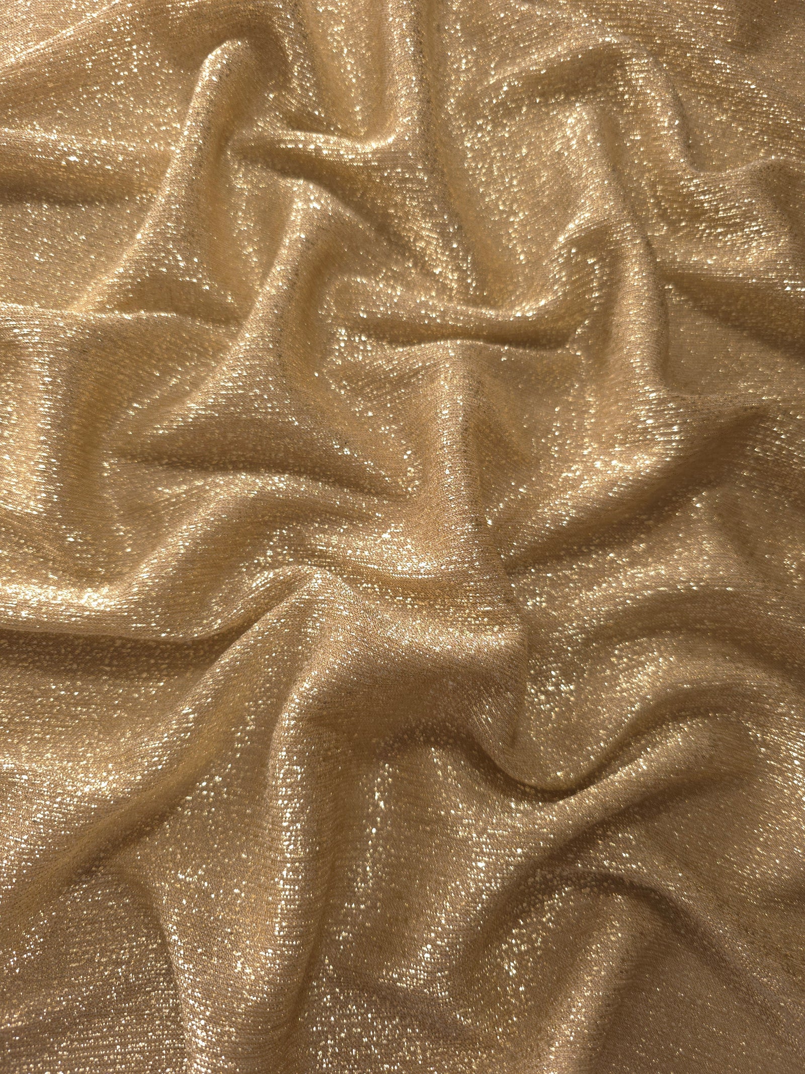 Draped Pale Gold Sheer Glitter Stretch Tulle Fabric showing scattered sparkle across fluid folds for eveningwear and stage looks