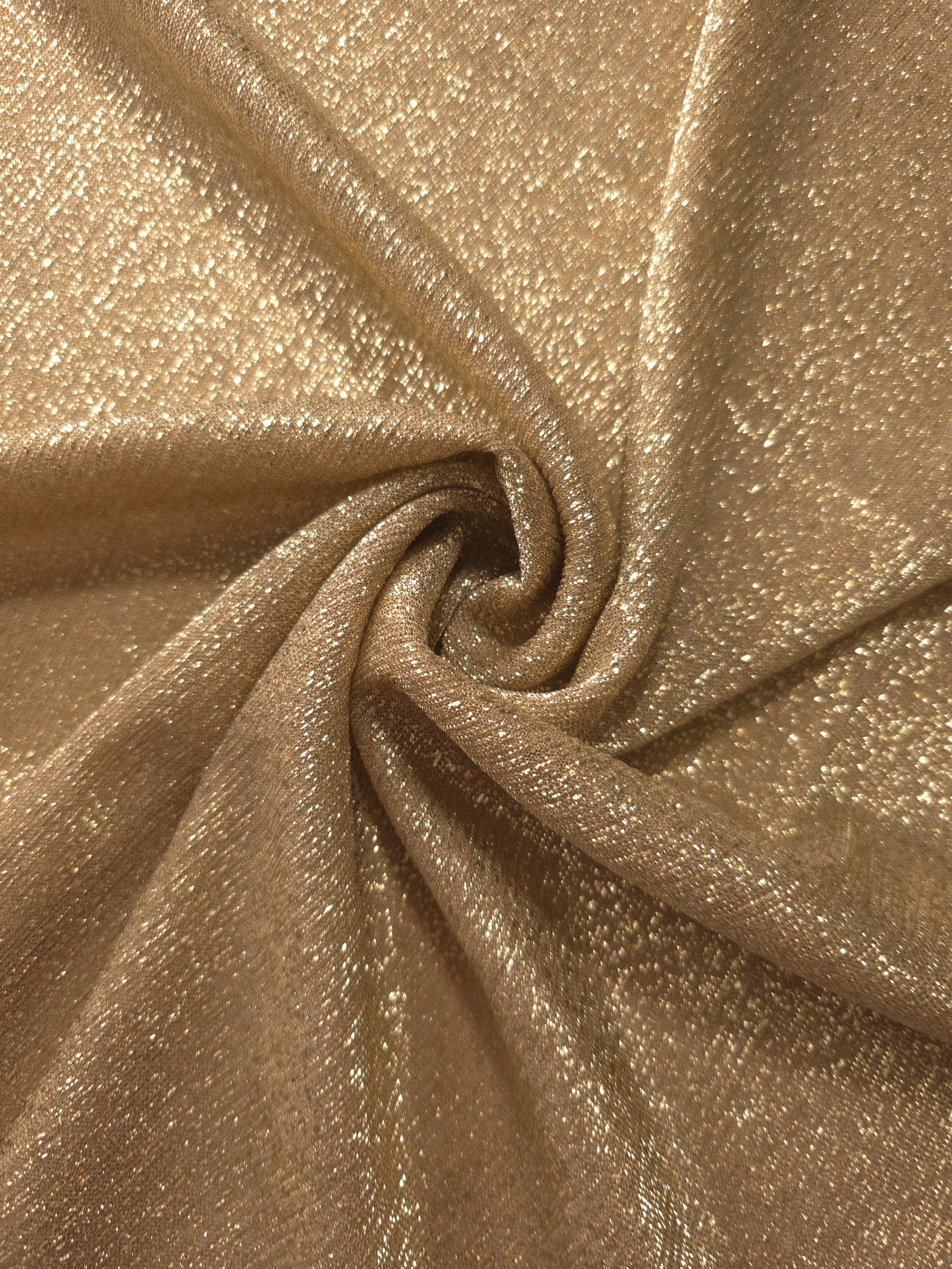 Swirl-draped Pale Gold Sheer Glitter Stretch Tulle Fabric capturing reflective sparkle and fluid movement through flexible folds