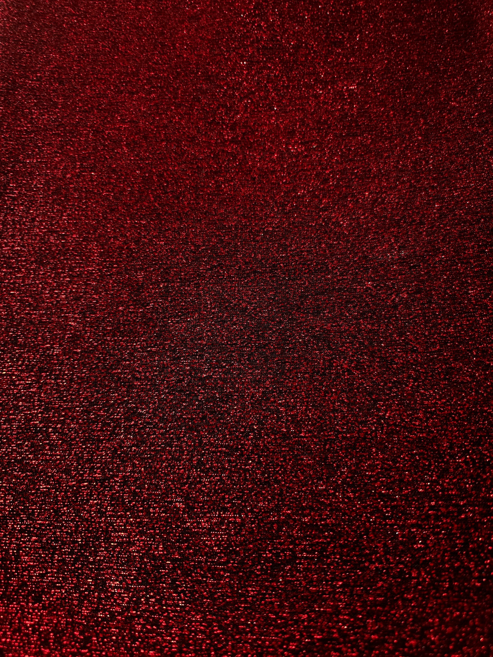 Surface detail of Ruby Red Sheer Glitter Stretch Tulle Fabric showing glitter coverage across the fine sheer tulle base