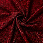 Swirl-draped Ruby Red Sheer Glitter Stretch Tulle Fabric capturing reflective sparkle and fluid movement through flexible folds