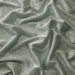 Draped Silver Sage Sheer Glitter Stretch Tulle Fabric showing scattered sparkle across fluid folds for eveningwear and stage looks