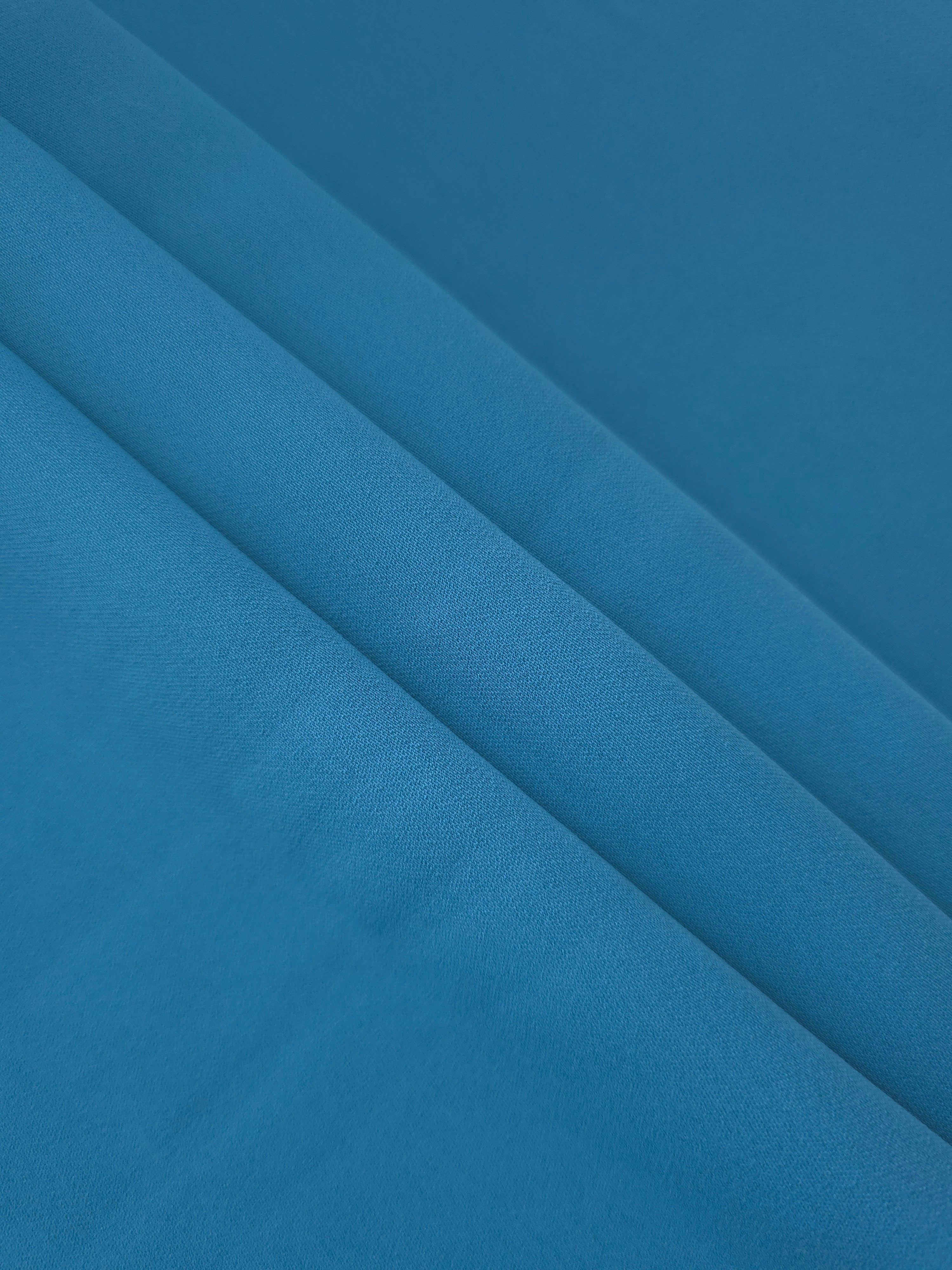 Layered Steel Blue mechanical polyester crepe showing soft body and gentle stretch for dressmaking and tailoring