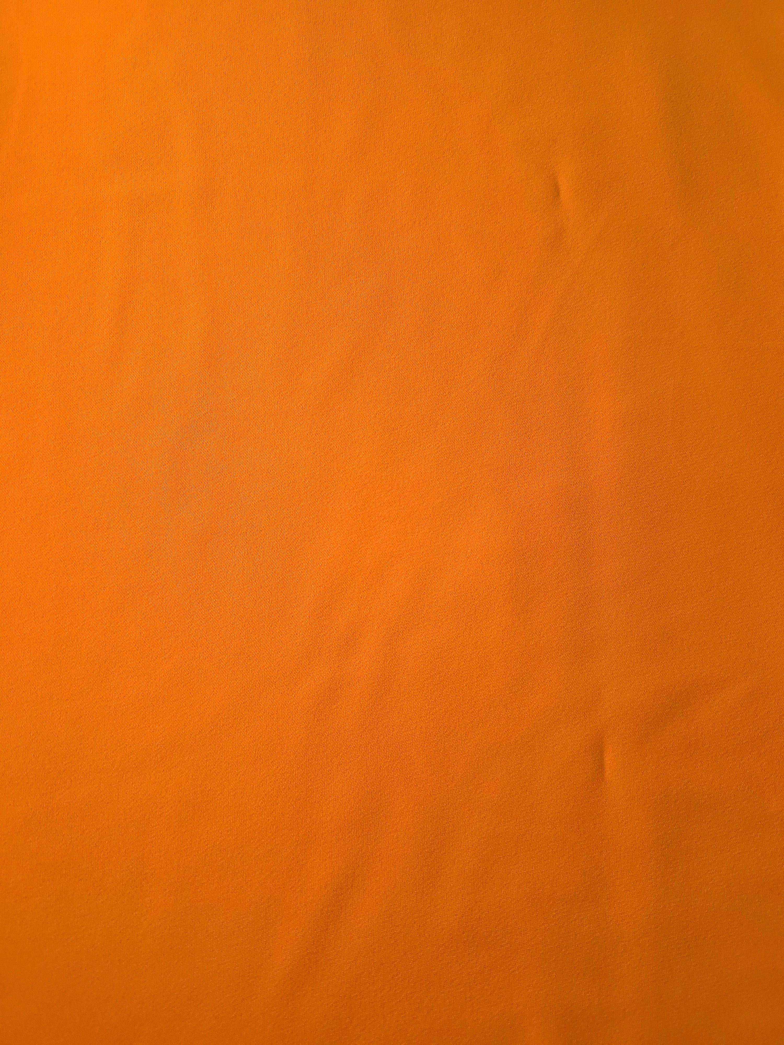 Flat surface of Tangerine Orange Italian polyester crepe, smooth apparel fabric for dresses and separates