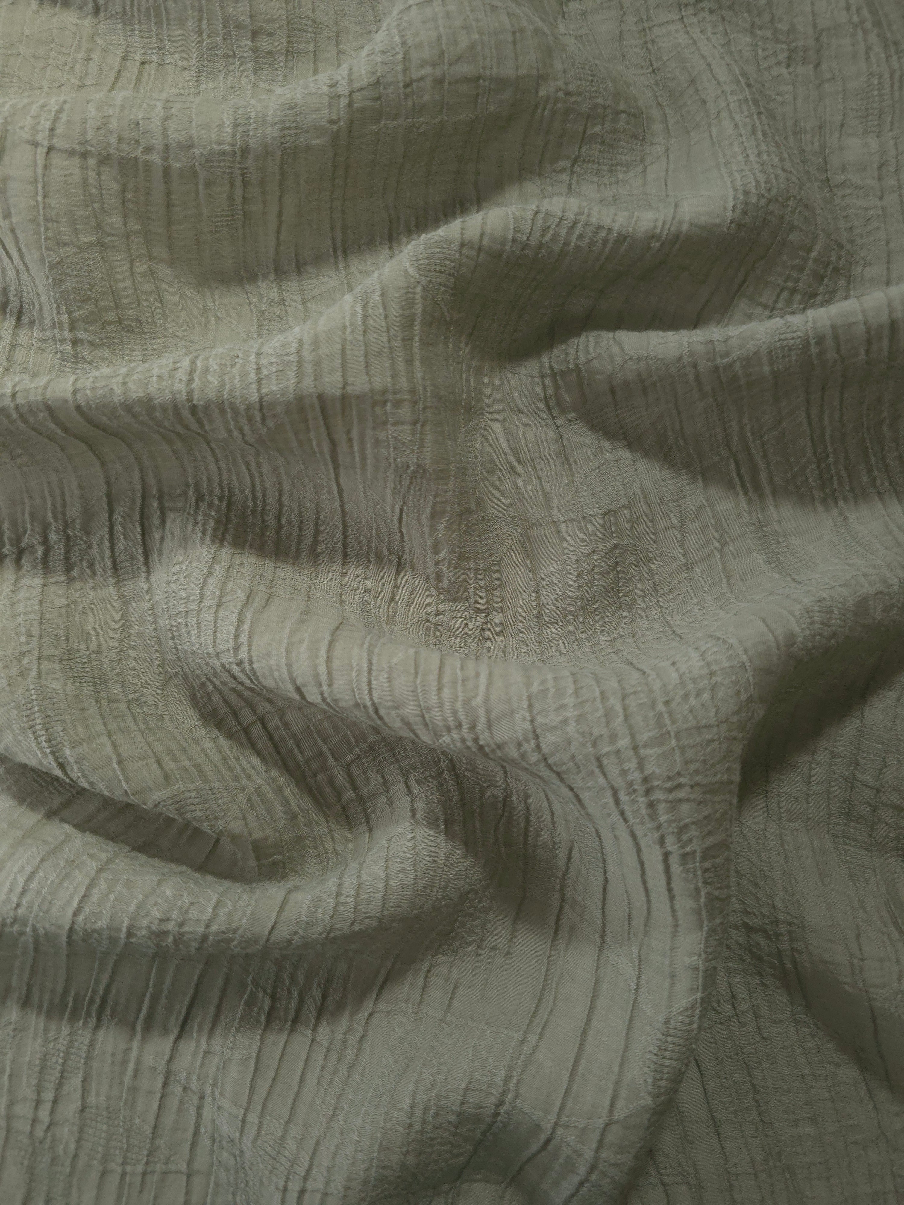 Fold detail of Sage Green Tencel jacquard with tonal leaf texture for dressmaking.