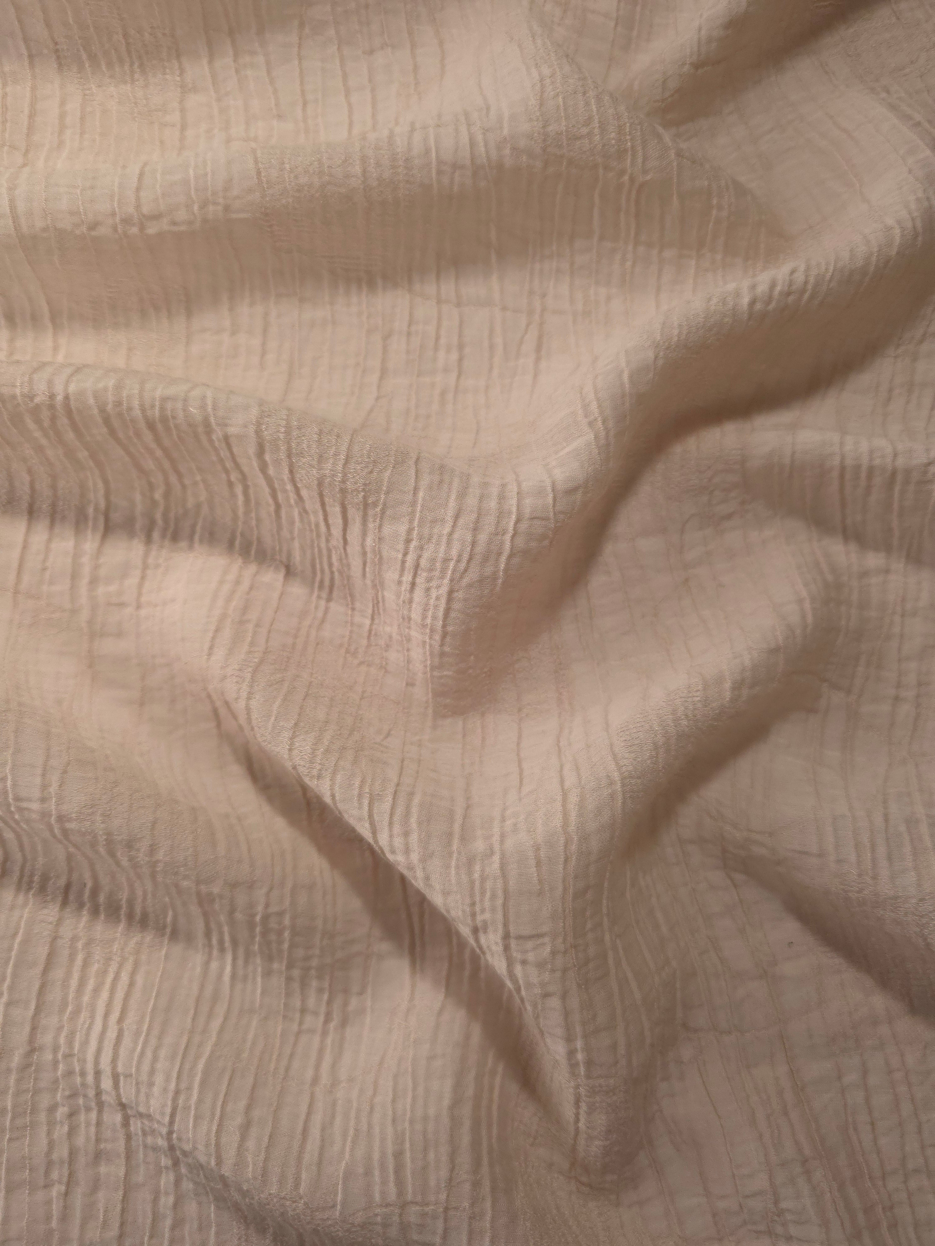 Fold detail of Soft Beige Tencel jacquard with tonal petal texture for dressmaking.