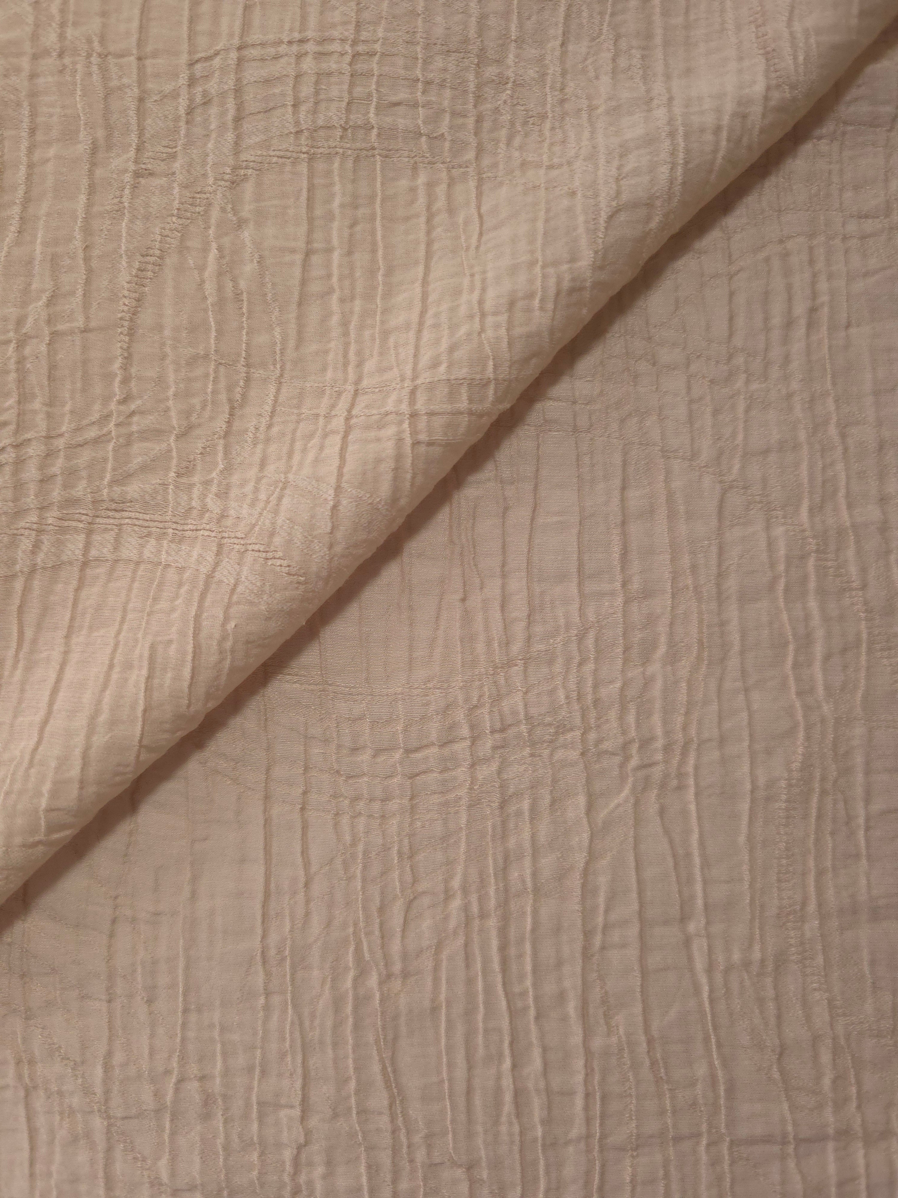 Folded Soft Beige Tencel jacquard with tonal swirl texture for blouse and skirt layers.