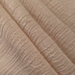 Fold detail of Soft Beige Tencel jacquard with tonal swirl texture for dressmaking.