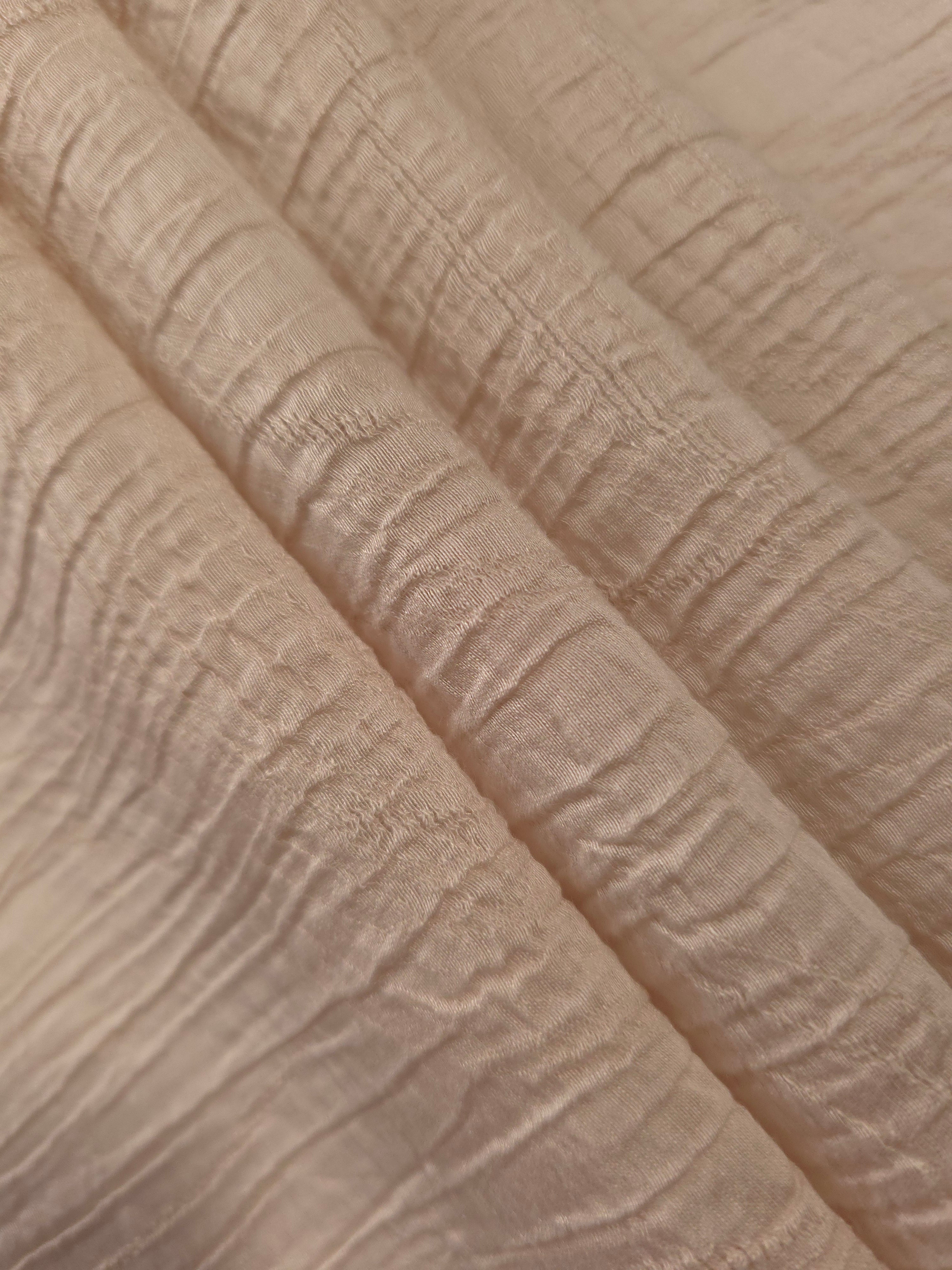 Fold detail of Soft Beige Tencel jacquard with tonal swirl texture for dressmaking.