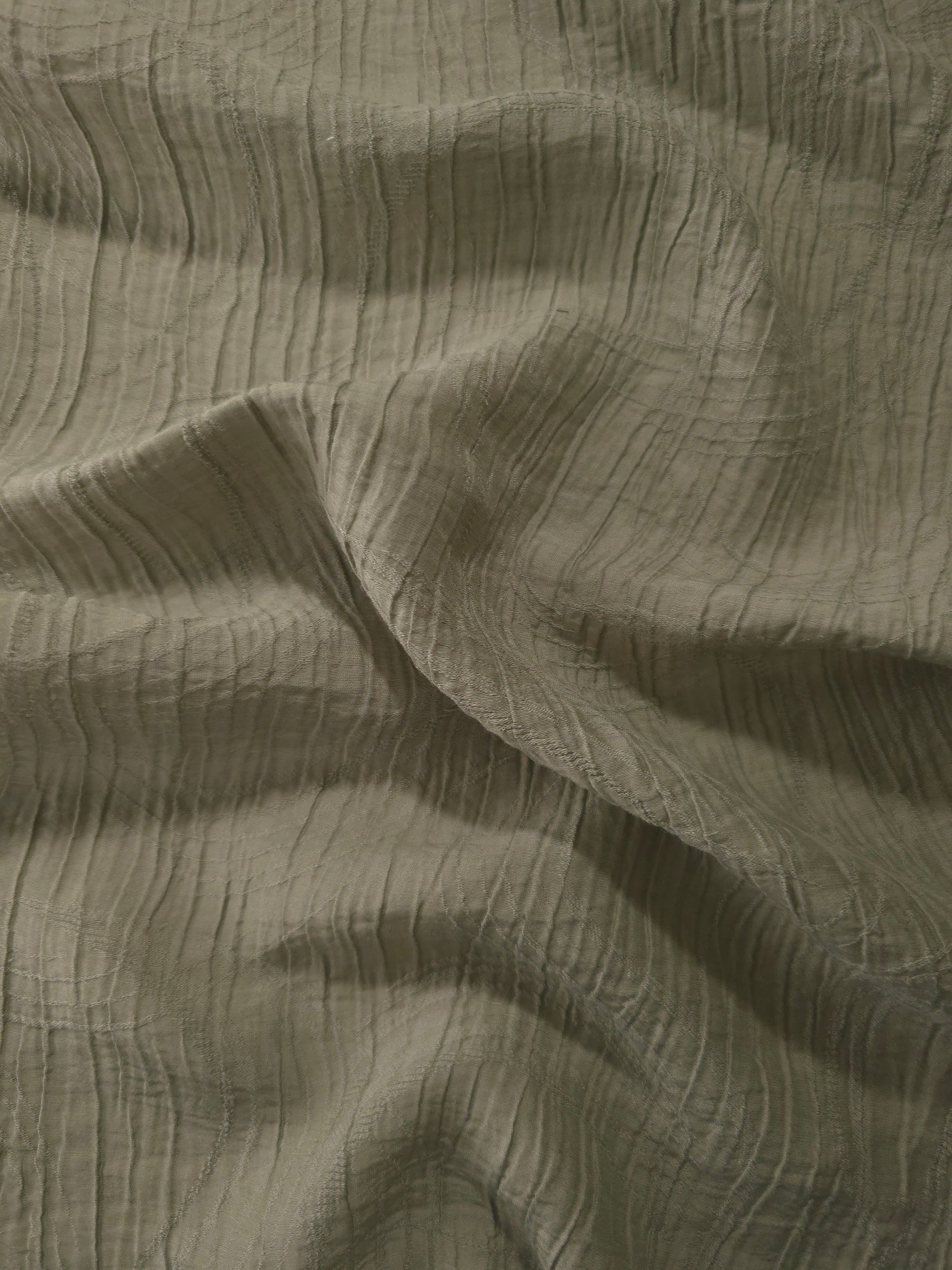 Detail view of Sage Green Tencel jacquard with tonal swirl texture for soft layers.