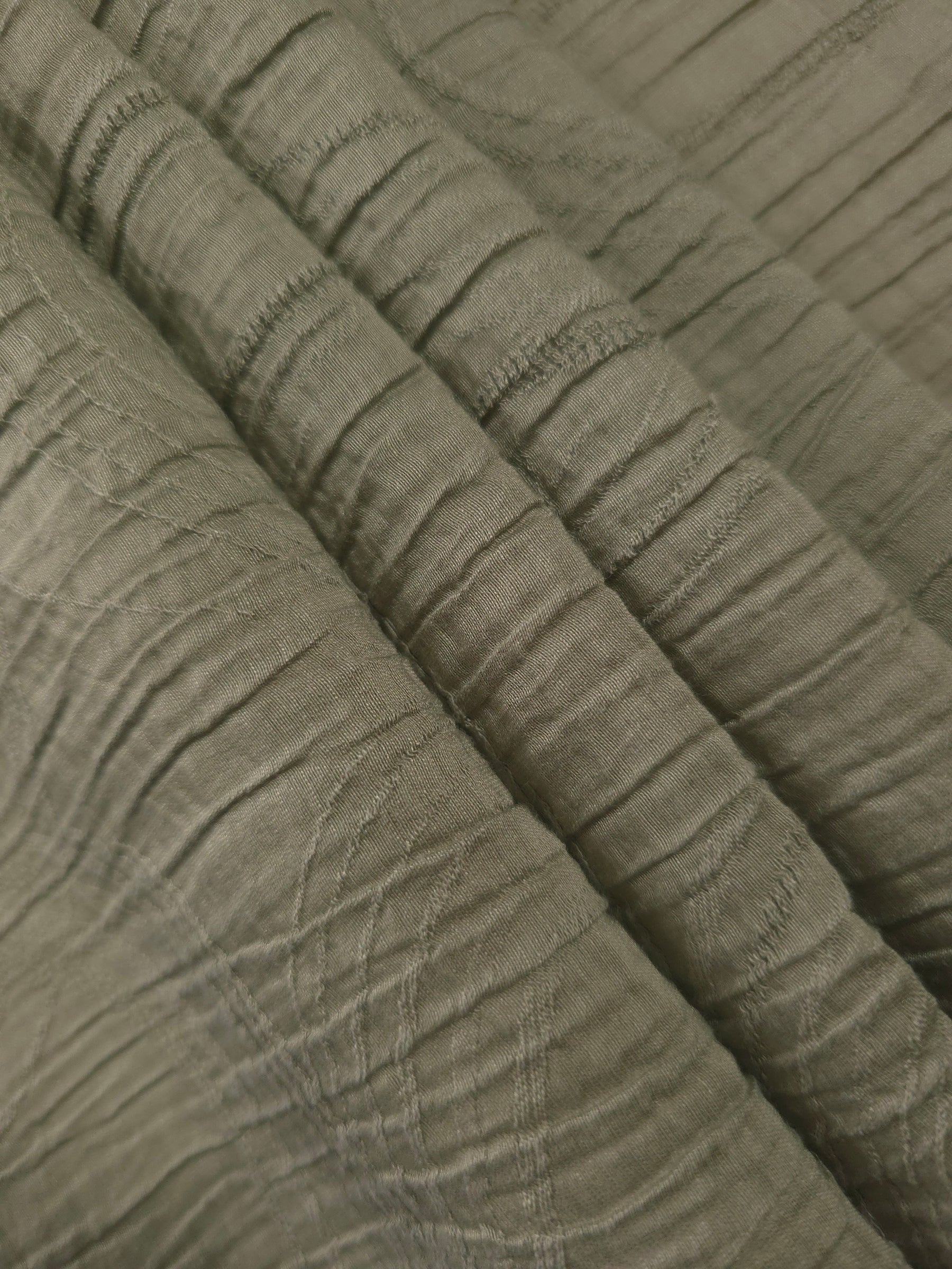 Fold detail of Sage Green Tencel jacquard with tonal swirl texture for dressmaking.