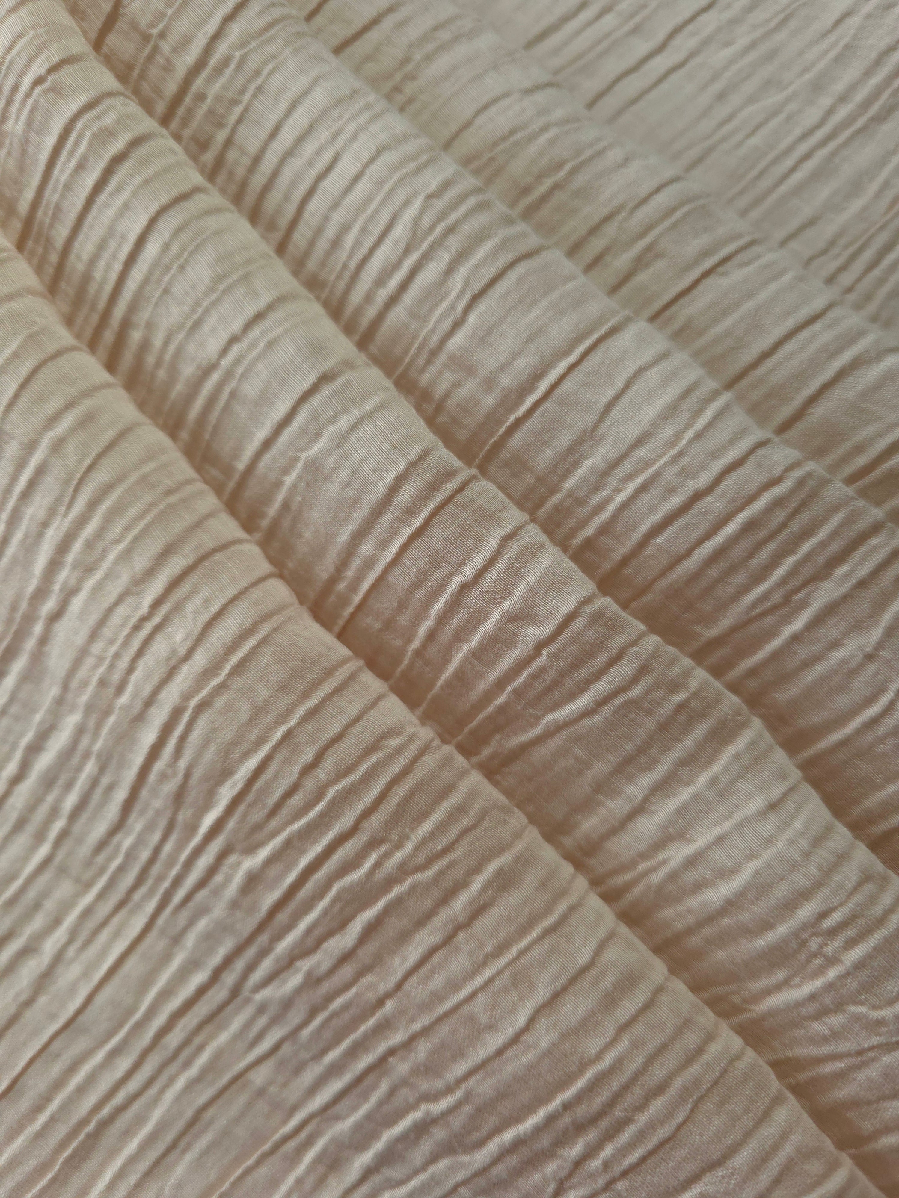 Folded Soft Beige Tencel jacquard with subtle woven texture for blouse and skirt layers.