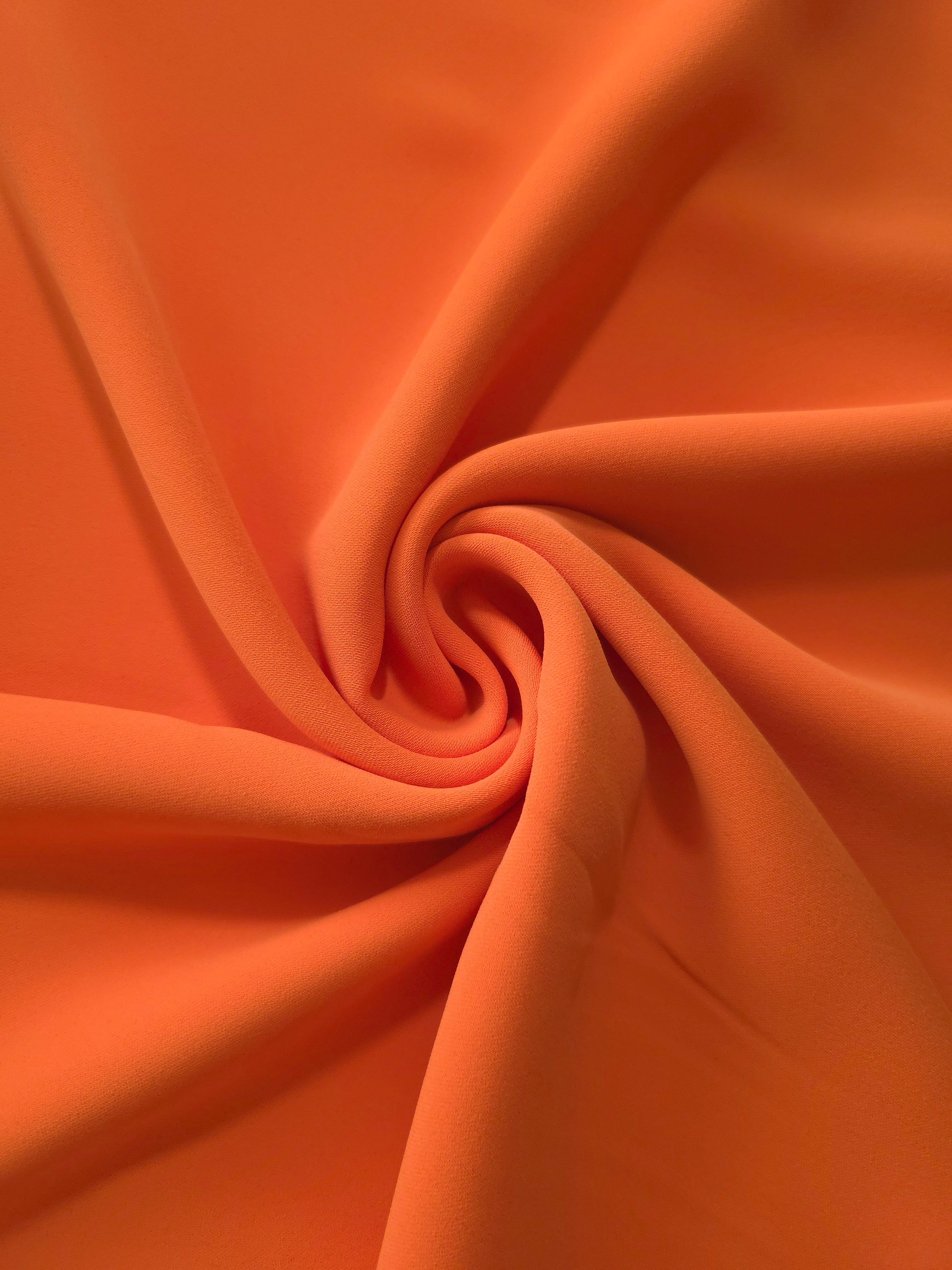 Terracotta Orange silky-feel polyester crepe styled in a swirl to show fluid dressmaking drape and movement