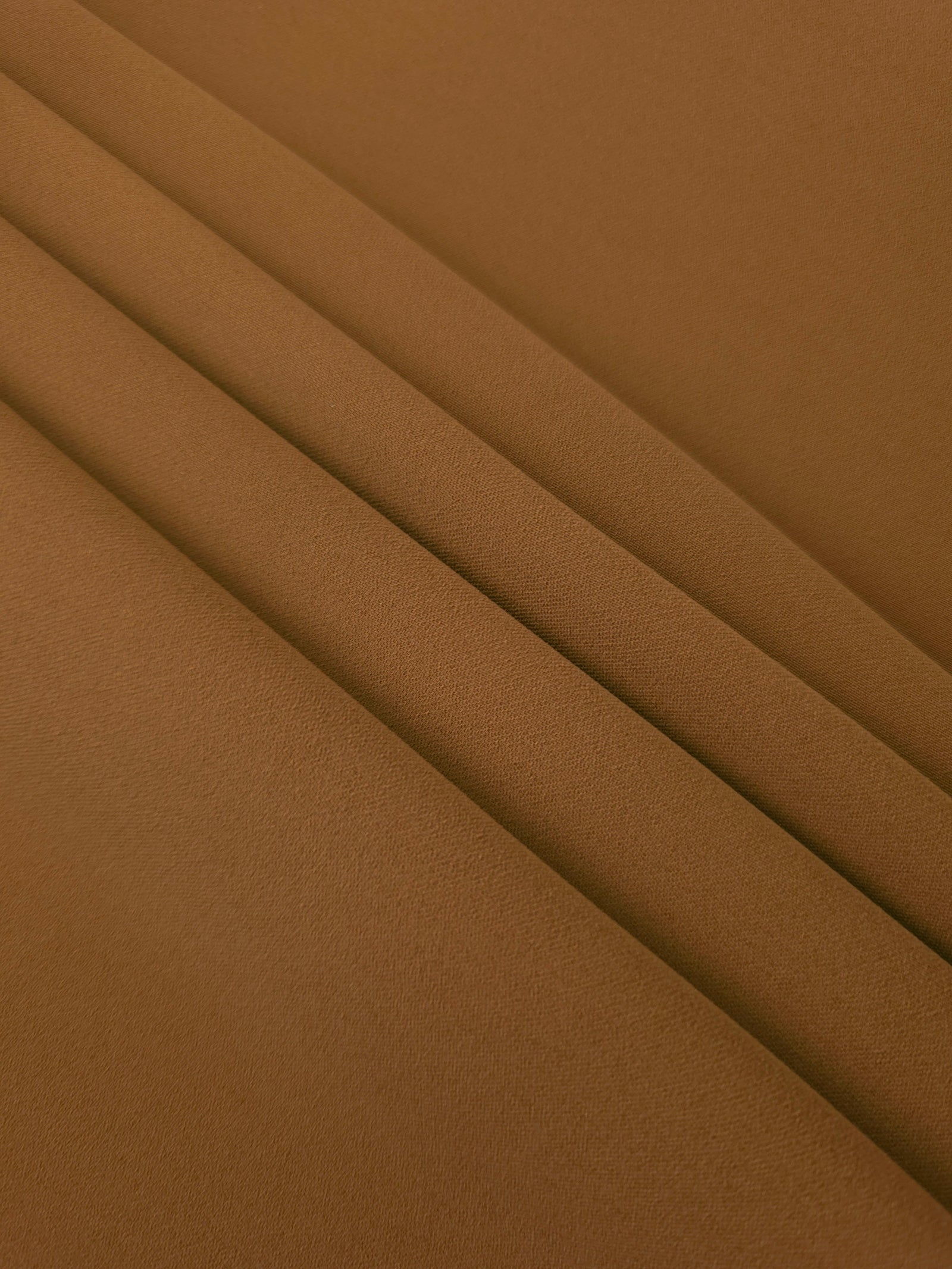 Layered Toffee Brown mechanical polyester crepe showing soft structure and slight mechanical stretch for tailoring