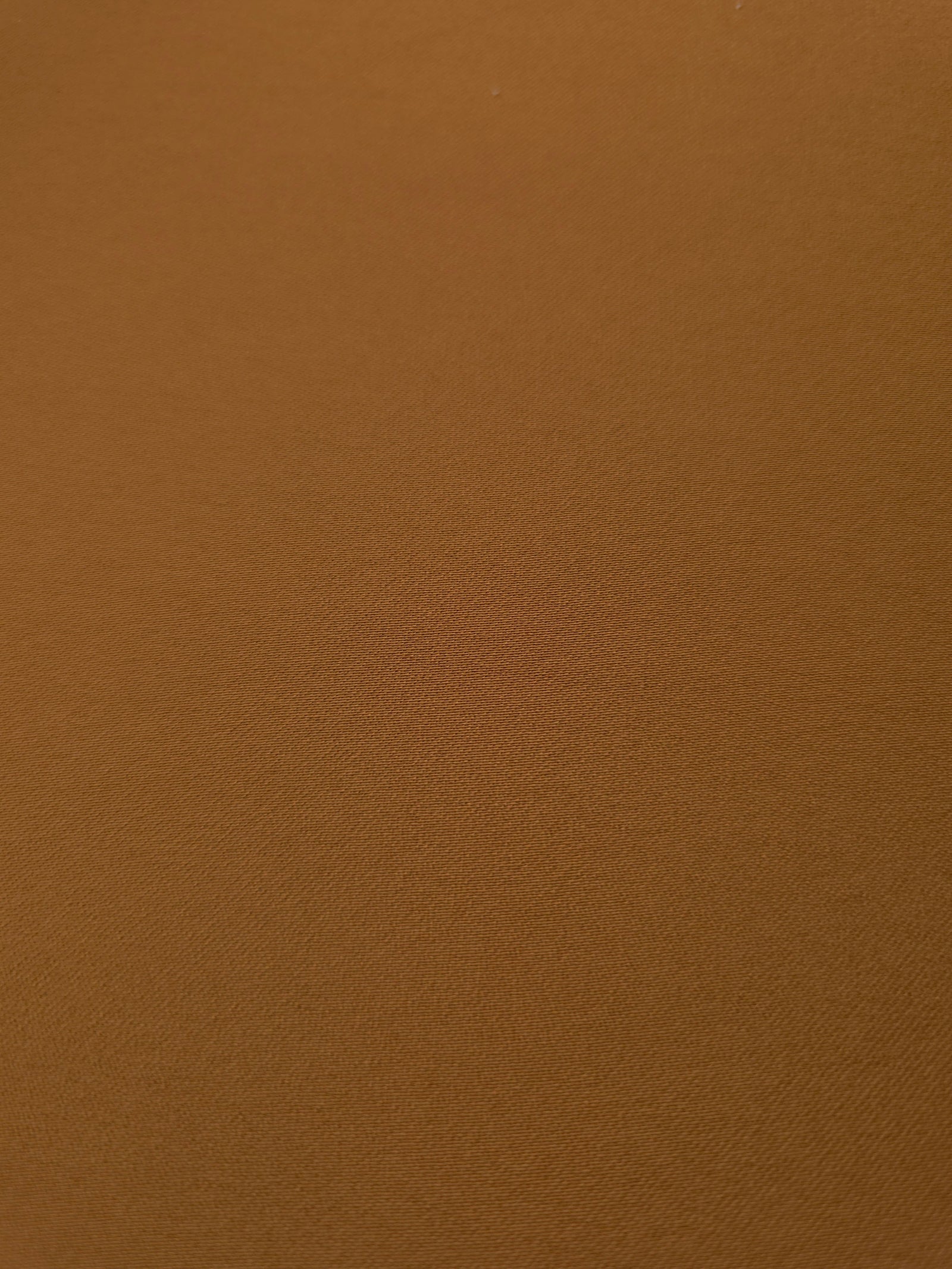 Close-up of Toffee Brown 100% mechanical polyester crepe showing fine woven texture and a silky-soft hand feel