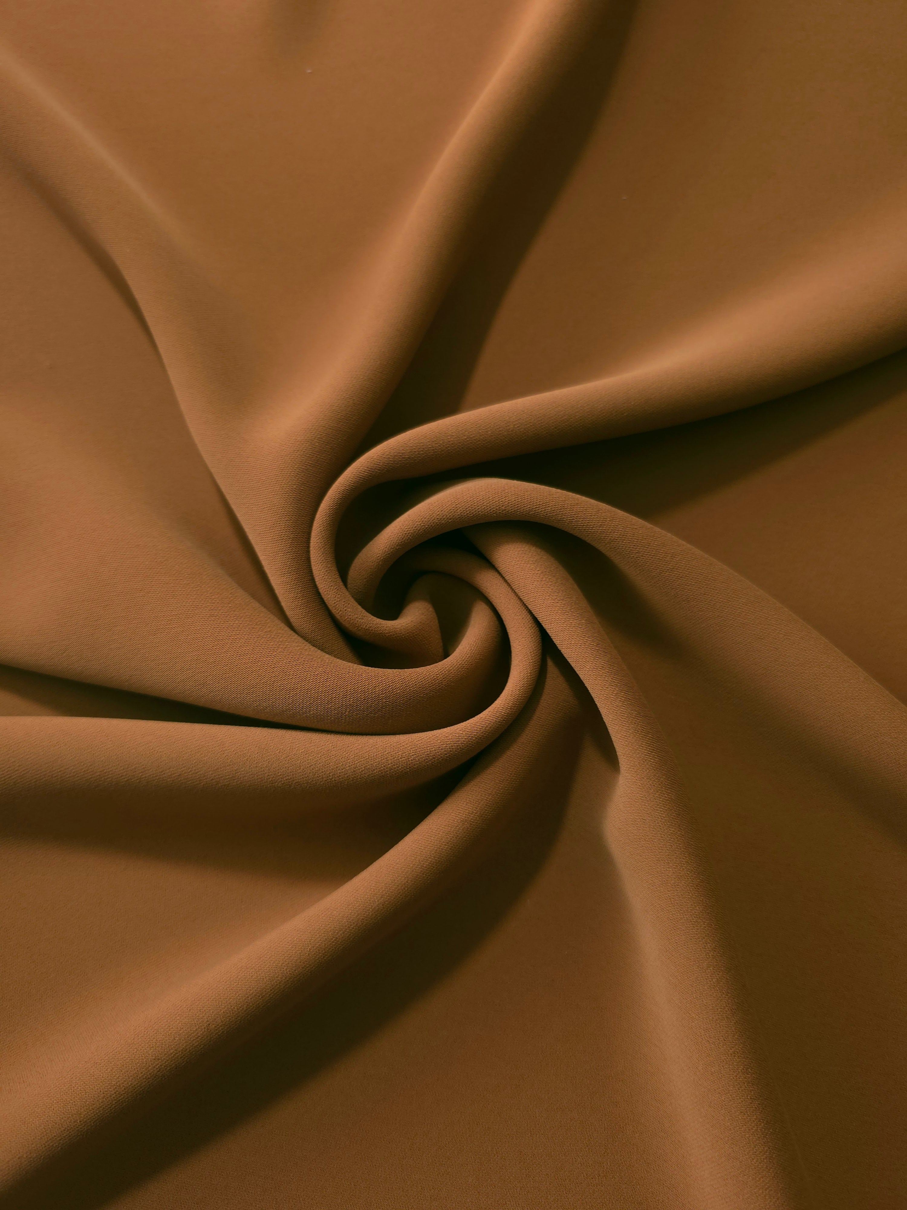 Toffee Brown polyester crepe arranged in a flowing swirl, showing drape used for abayas and modest fashion