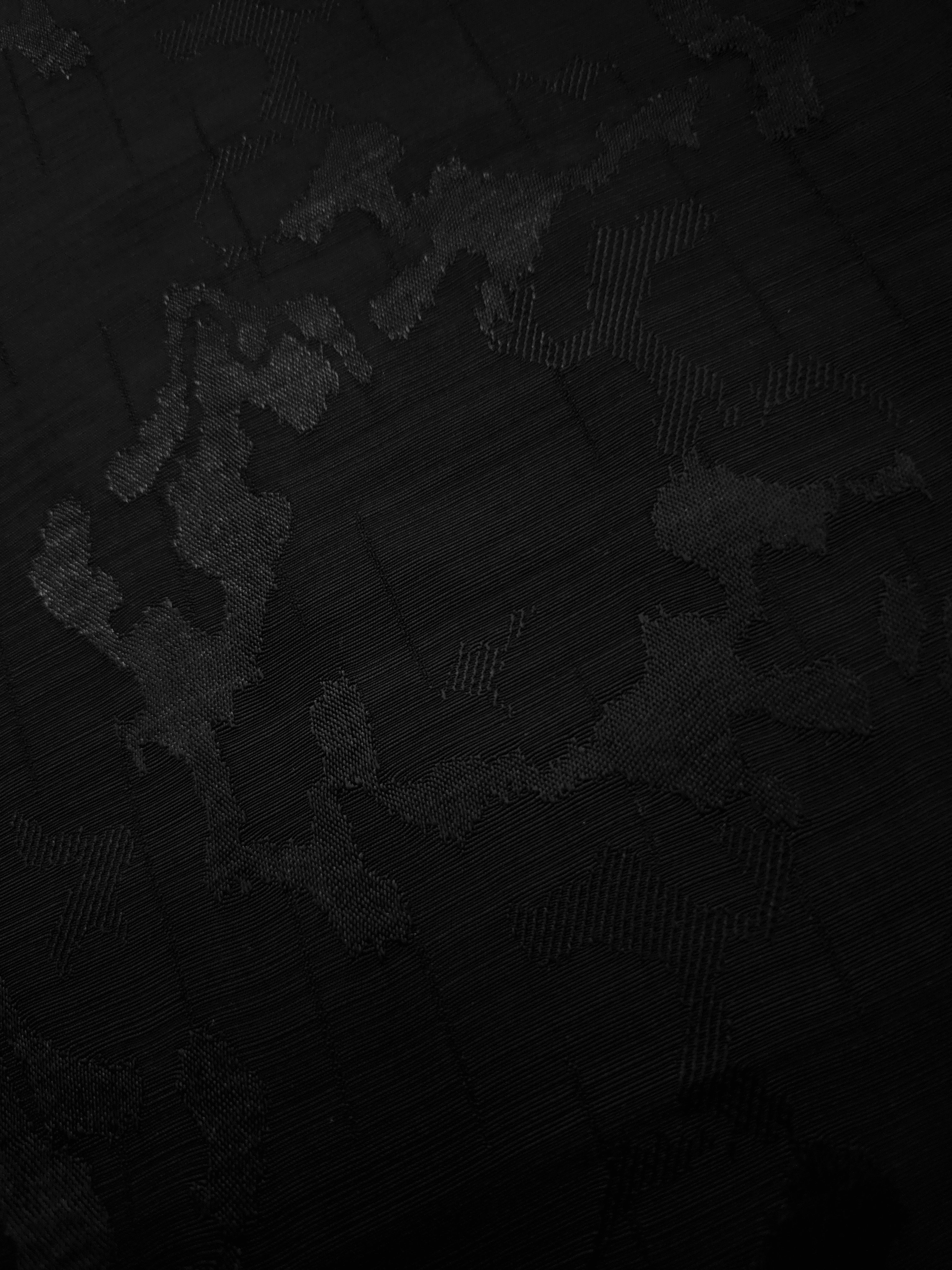 Macro view of jet black botanical jacquard weave and tonal finish for refined blouses, formal tunics and dressmaking details.