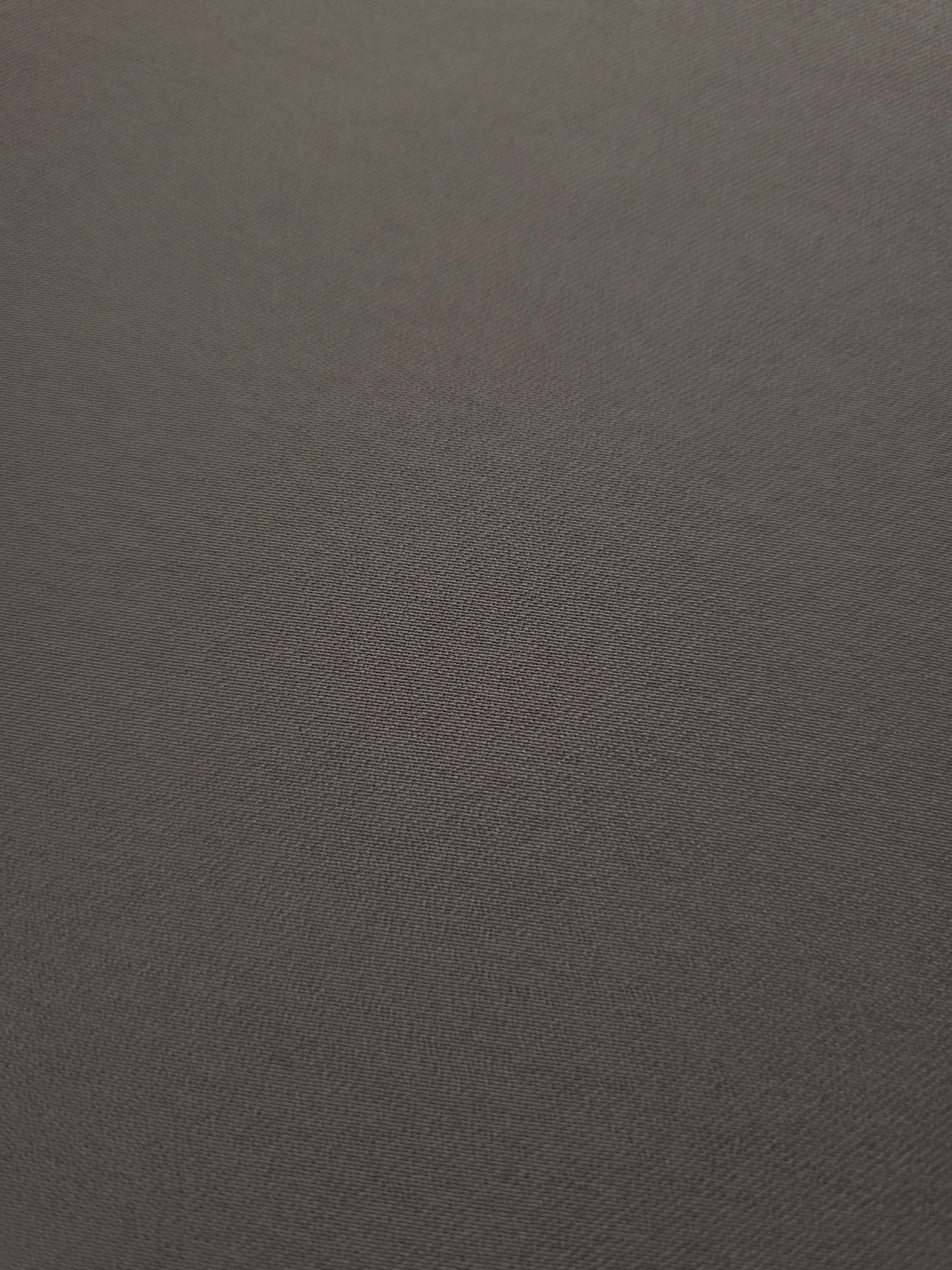 Close-up of Warm Charcoal Gray 100% mechanical polyester crepe showing fine woven texture and a silky-soft hand feel