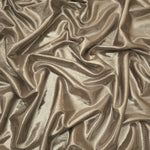Draped Warm Greige Beige metallic foiled spandex showing reflective folds and flexible flow for dresses, stagewear and occasion looks