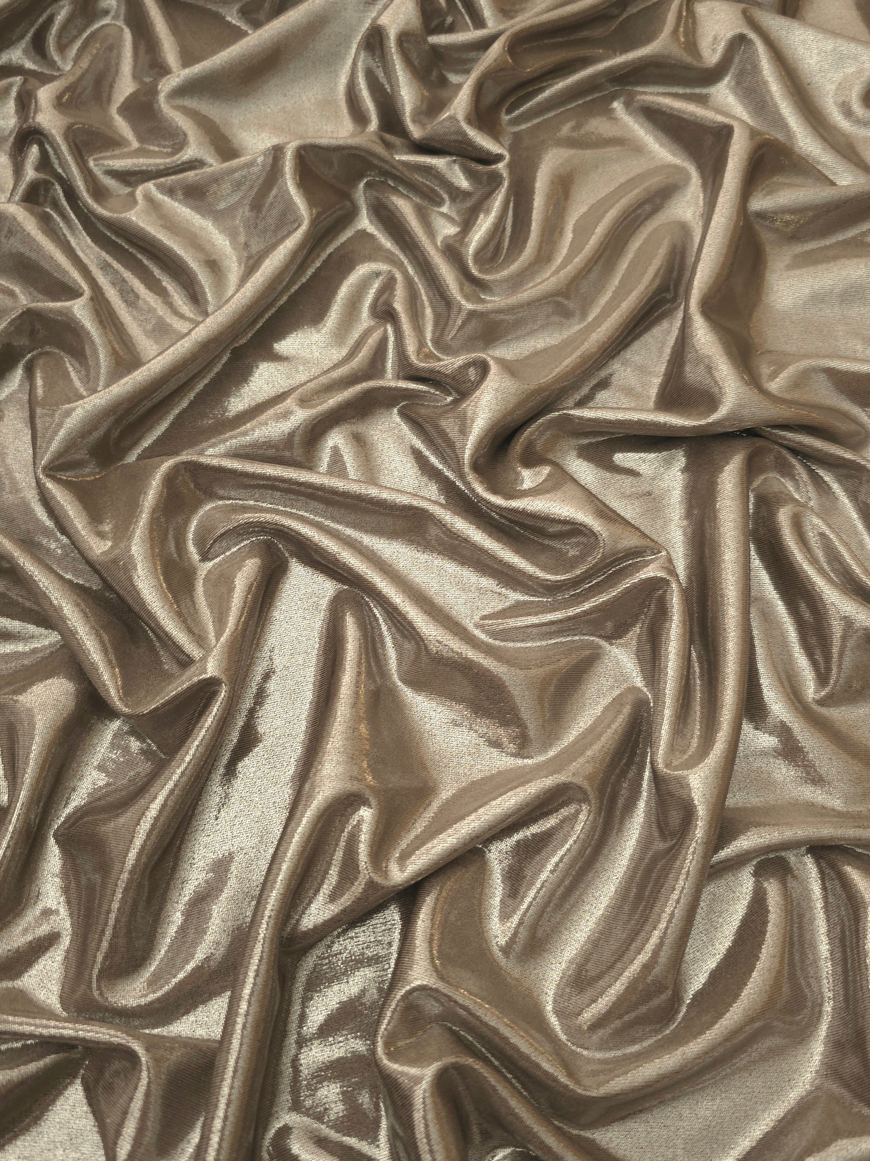 Draped Warm Greige Beige metallic foiled spandex showing reflective folds and flexible flow for dresses, stagewear and occasion looks