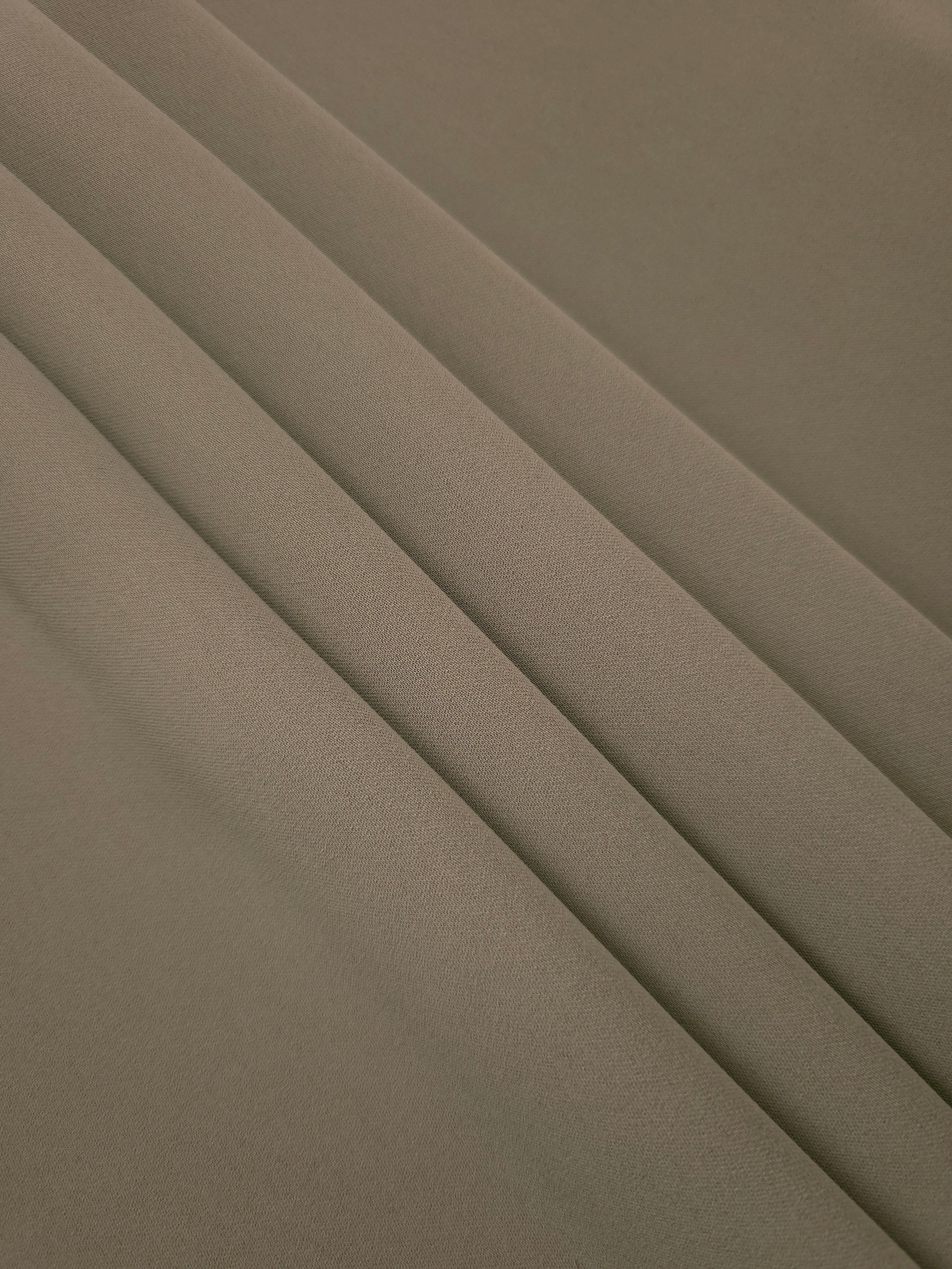Layered folds of Warm Stone Taupe 100% mechanical polyester crepe showing body and gentle construction stretch