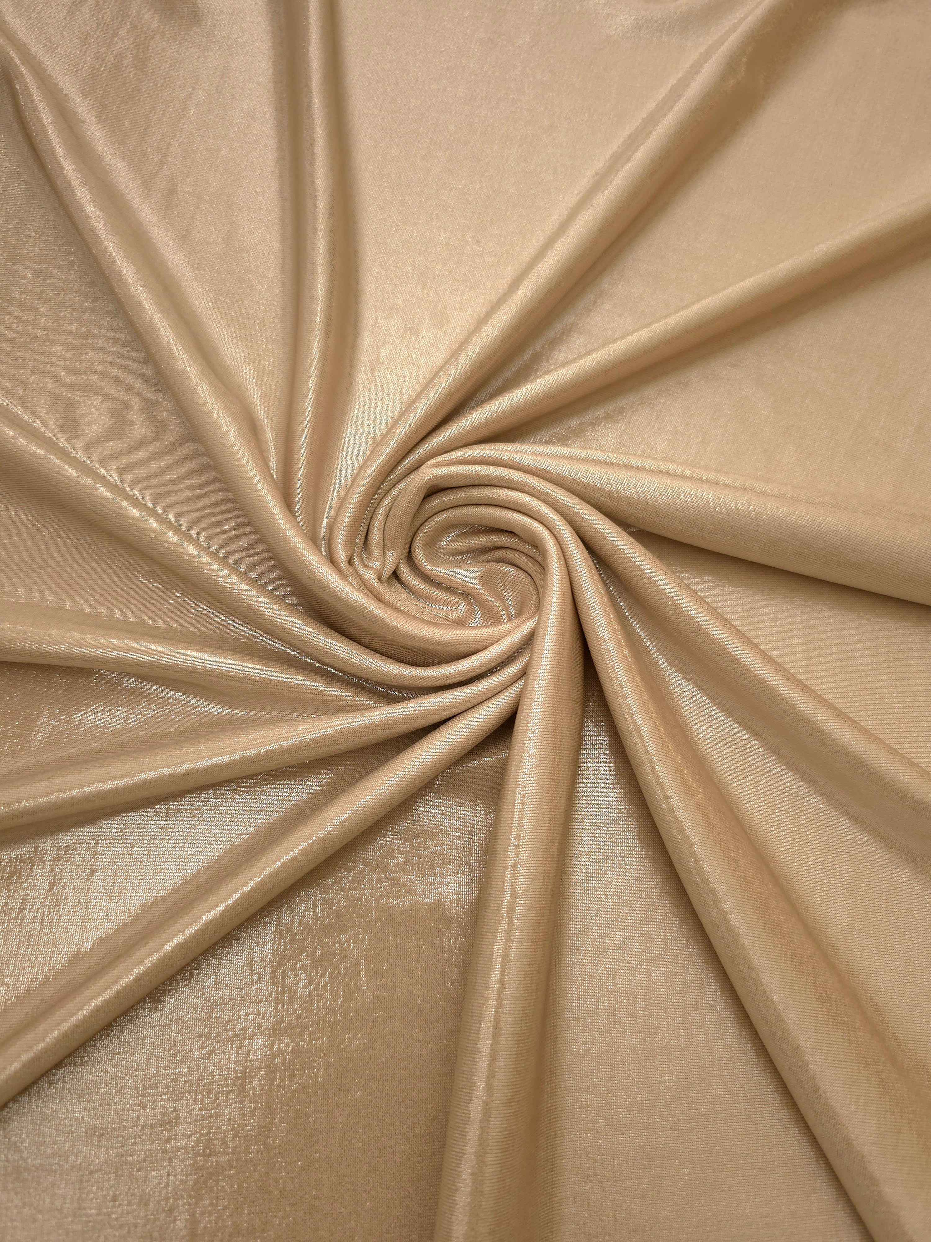 Warm Taupe Beige shimmer foiled stretch fabric arranged in a swirl, highlighting movement and reflective finish for performancewear